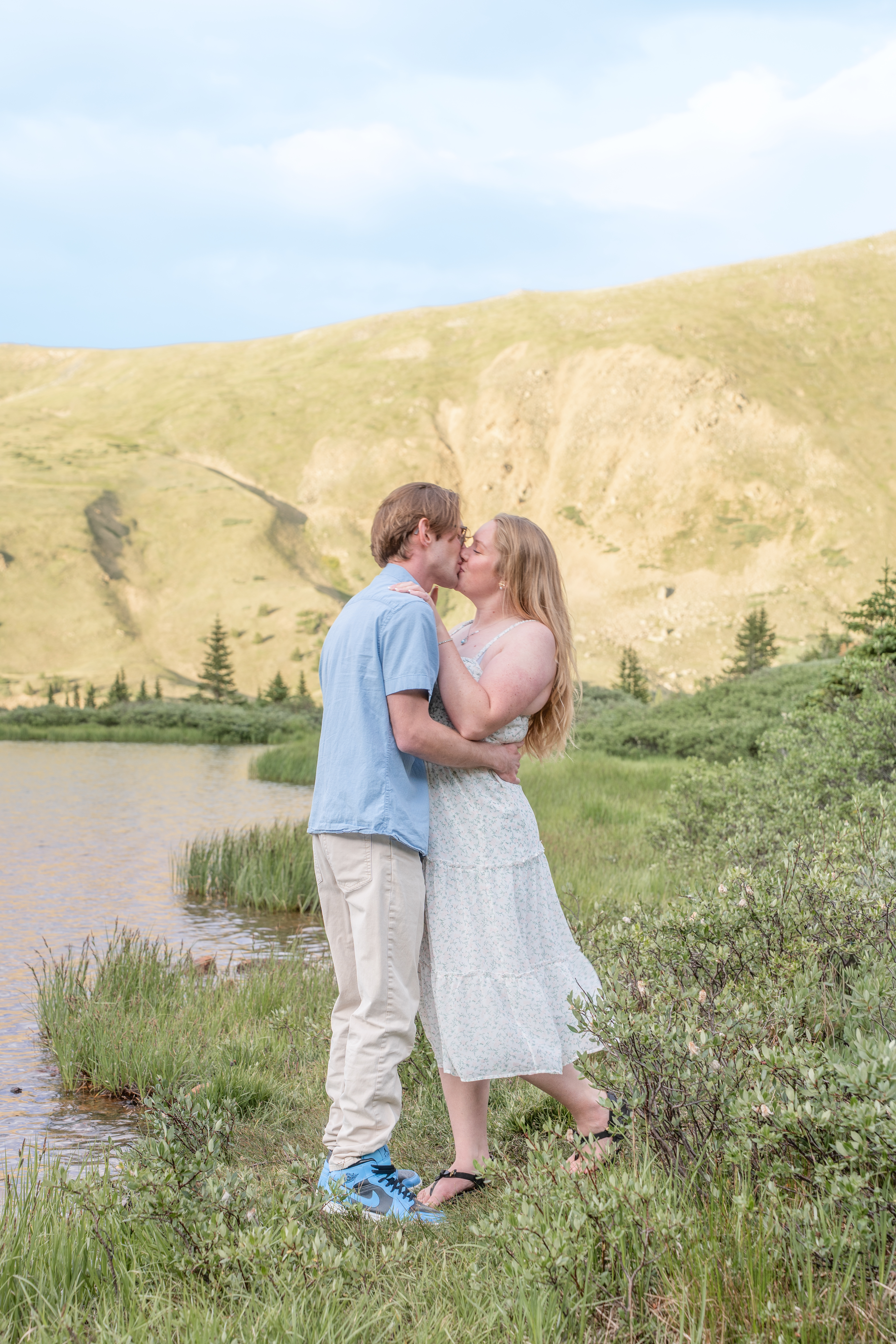 Jerome and Reese kissing beside an alpine lake